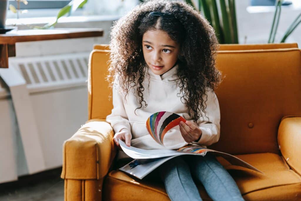 Menina no sofá com livro. Imagem ilustrativa texto leitura desenvolve.